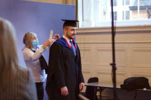 A graduand has their gown fitted