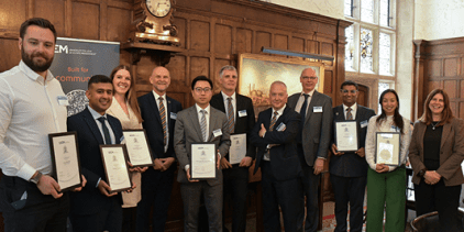 Seven new Associate Fellows presenting their certificates, posing in a row with Chair Peter McCrea, Vice Chancellor Ashley Wheaton and Deputy Vice Chancellor Jane Fawkes