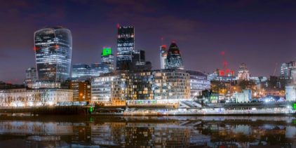 Beautiful cityscape of London at night with skyscrapers reflecting in the Thames River.