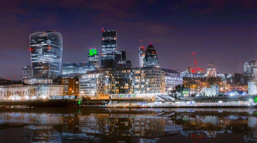 Beautiful cityscape of London at night with skyscrapers reflecting in the Thames River.